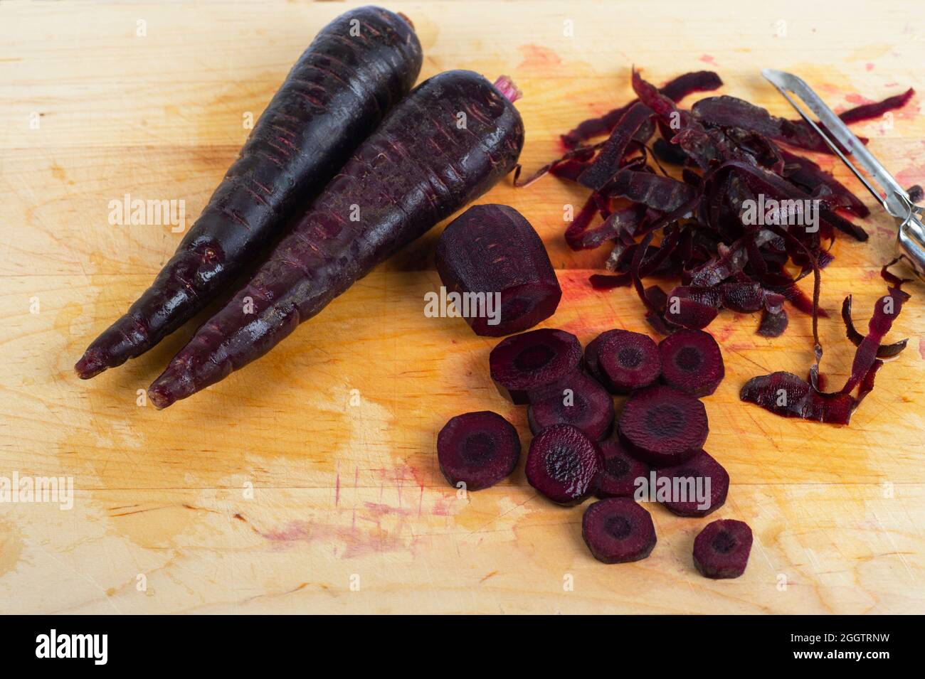 Organic black carrots, peeled and sliced on a cutting board. Stock Photo