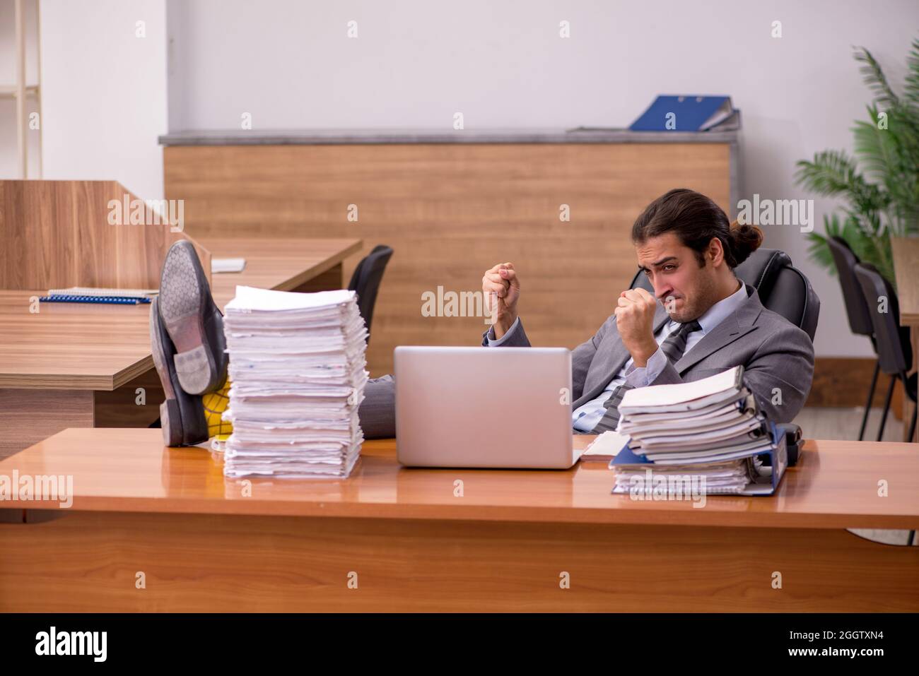 Young employee and too much work in the office Stock Photo - Alamy