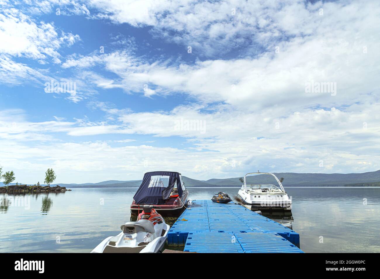 Miass, Russia - June 7, 2016: boats near pier on lake in background blue sky and mountains Stock Photo