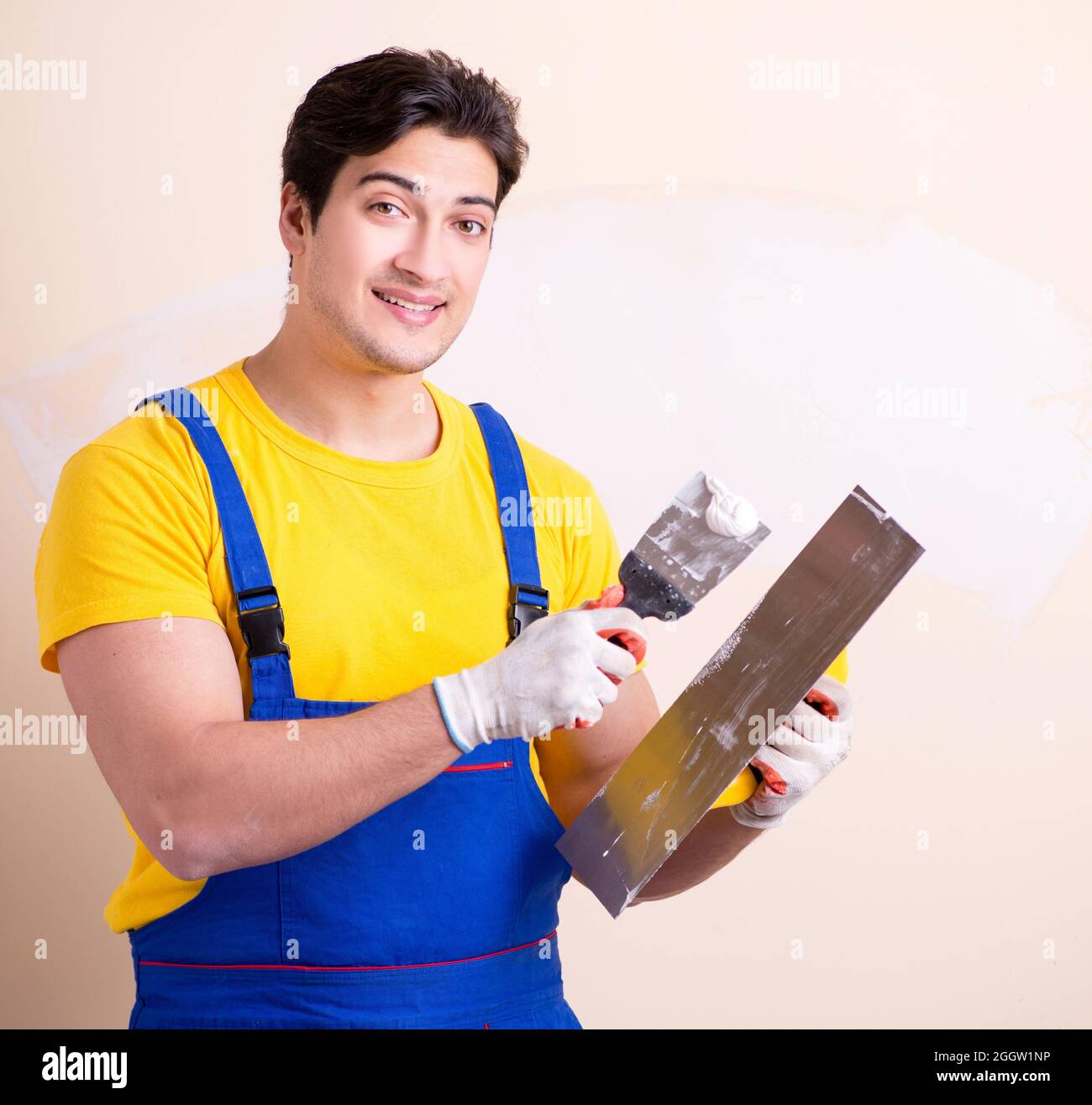 The young contractor employee applying plaster on wall Stock Photo