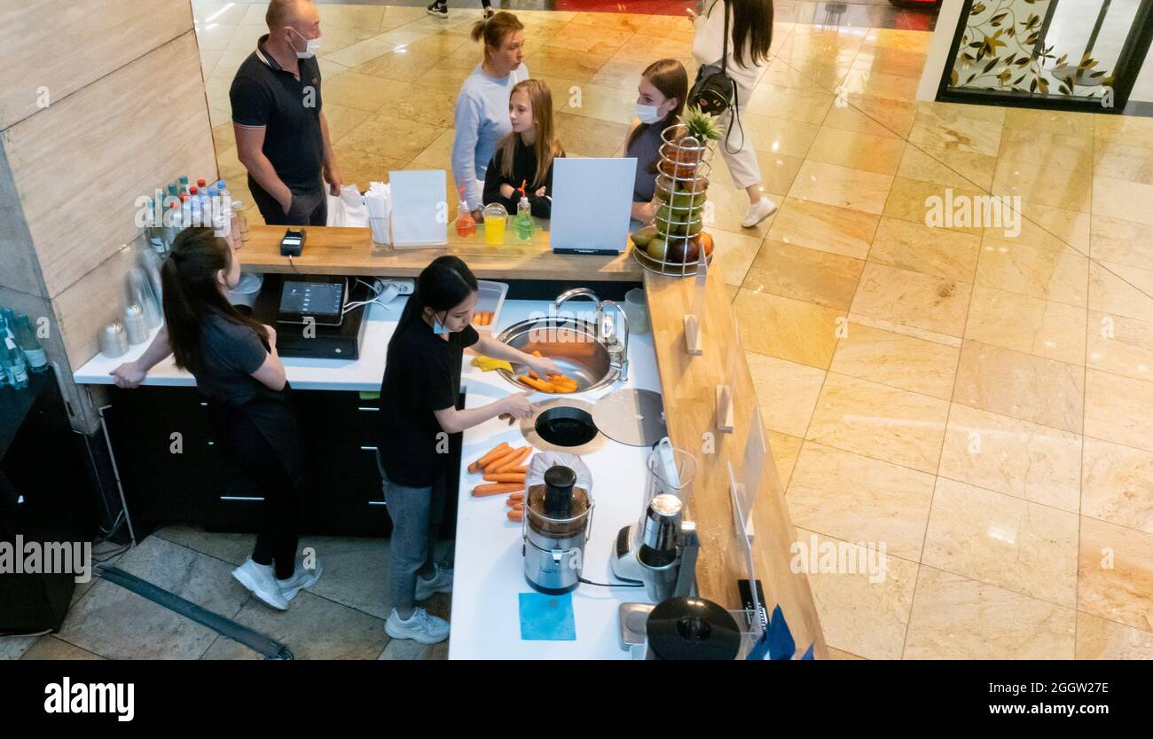 Workers at the food and drinks kiosk prepare carrot for juices at the stand inside the mall, Moscow, Russia Stock Photo