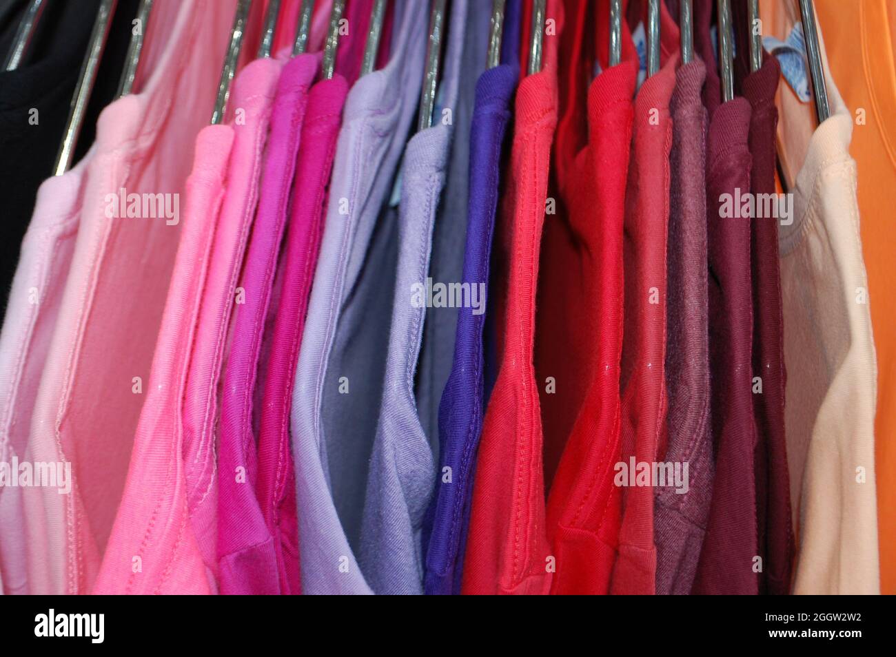 colored t-shirts hanging on hangers with color ranges Stock Photo