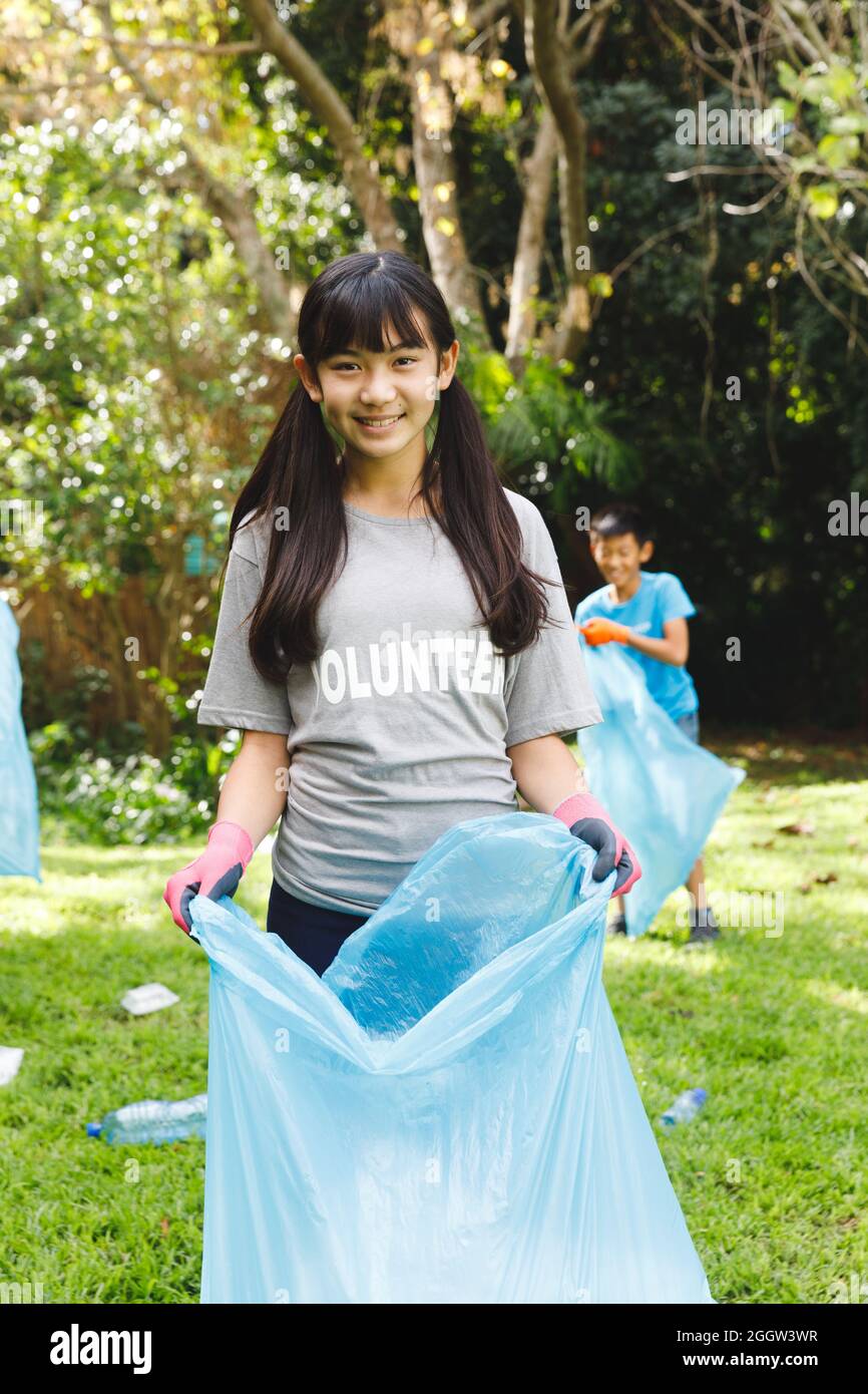 Portrait of smiling asian daughter putting rubbish in refuse sacks with family in the countryside Stock Photo