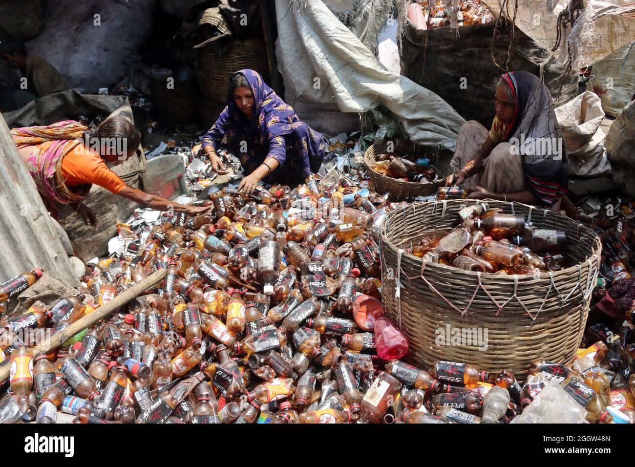 Laborers sort through polyethylene terephthalate (PET) bottles in a recycling factory in Dhaka