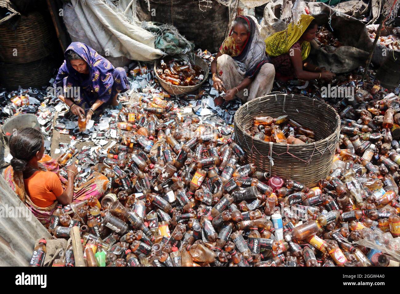 Laborers sort through polyethylene terephthalate (PET) bottles in a recycling factory in Dhaka
