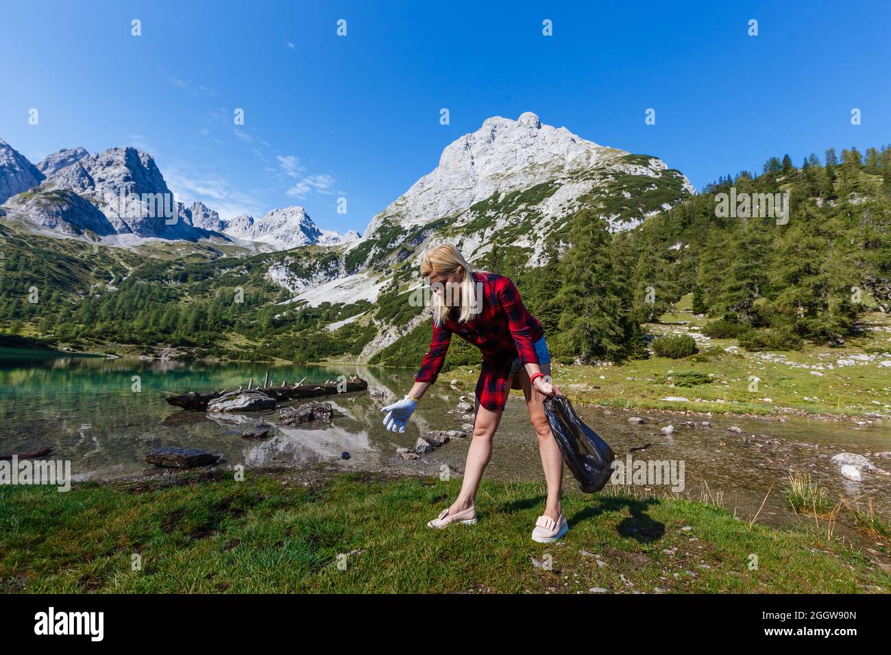 Eco hiker hand collecting garbage in the grass of the mountain Stock Photo