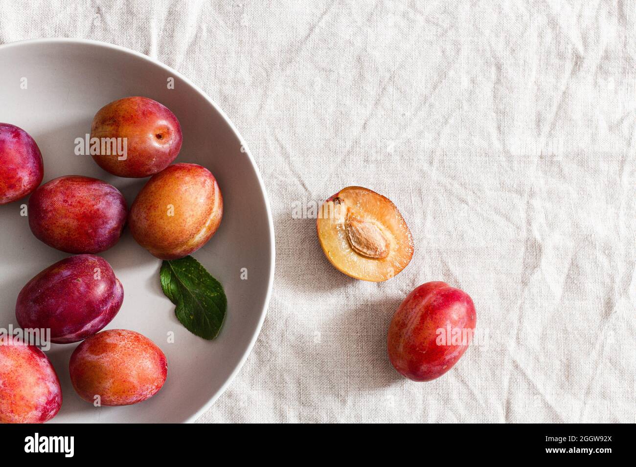 Victoria plums in a grey bowl over beige linen tablecloth. Stock Photo