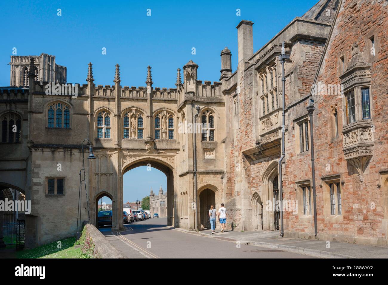 Wells UK architecture, view in summer of people entering the medieval arched gatehouse that separates St Andrew Street from Cathedral Green, Wells. Stock Photo