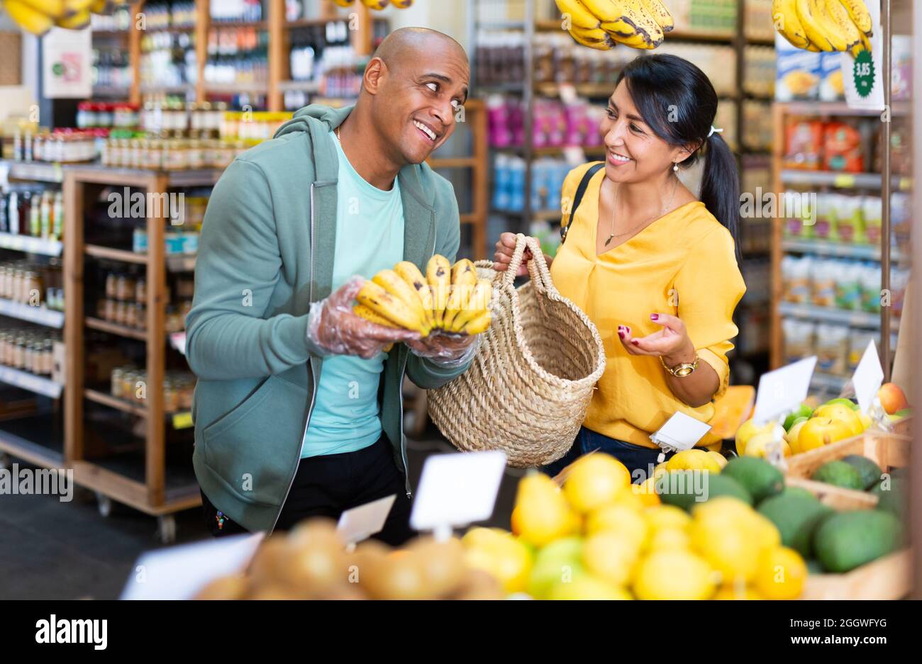 Hispanic married couple choosing bananas in grocery store Stock Photo