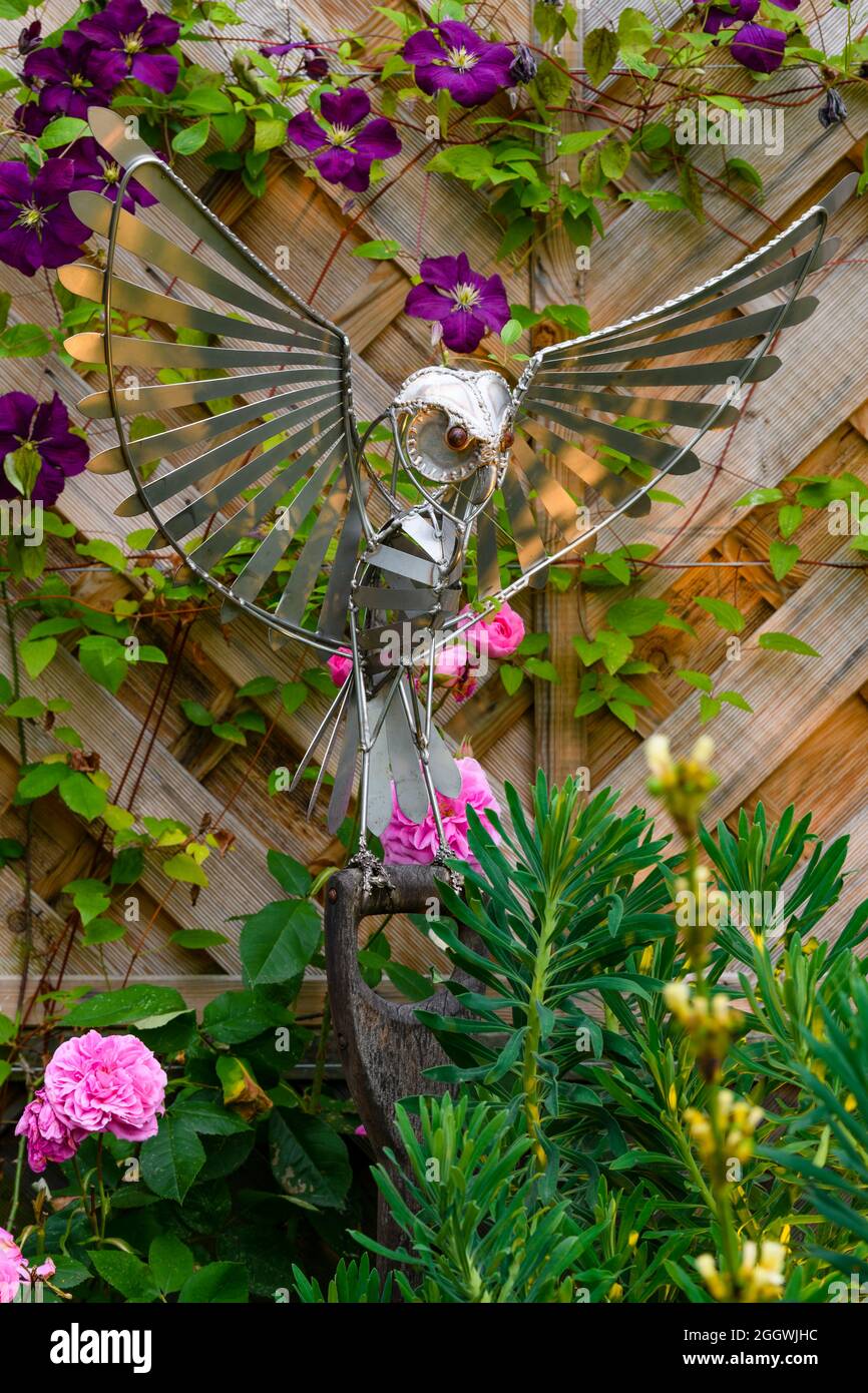 Landscaped sunny private garden close-up (sculptural handcrafted artwork of metallic bird & colourful summer border flowers) - Yorkshire, England, UK. Stock Photo