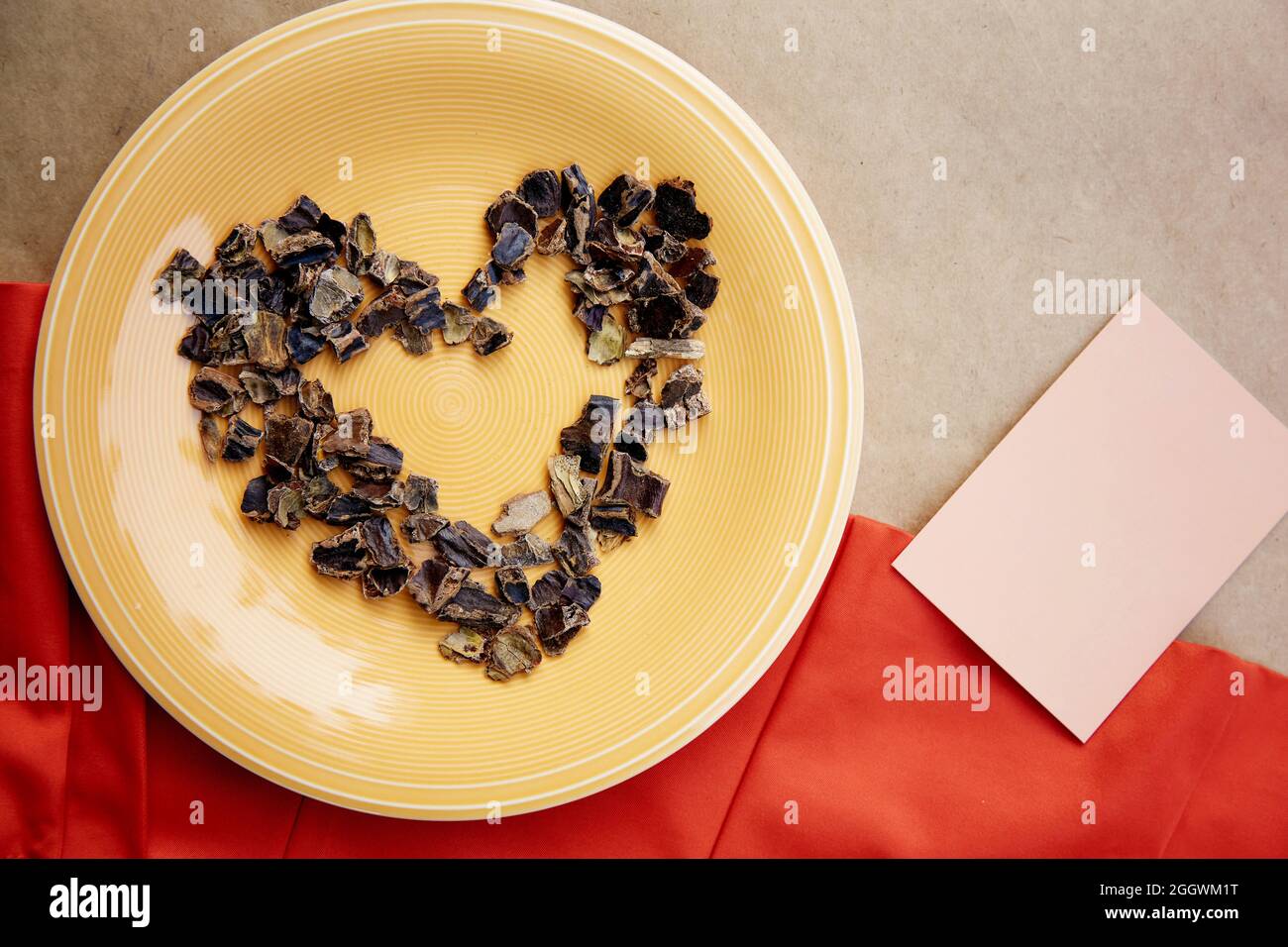 Carob in shape of heart symbol of coffee alternative - natural product on the plate. Organic plant-based caffeine antioxidants. Mock up of business ca Stock Photo