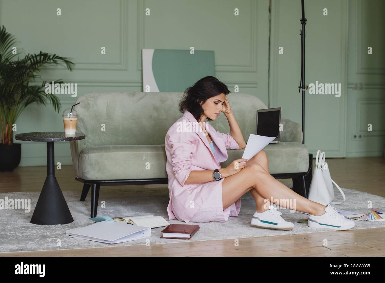 Business woman working at home with documents and laptop sitting on the floor. Stock Photo