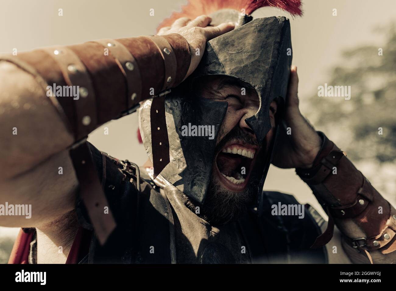 Portrait of screaming in rage ancient Spartan warrior in battle dress  against sky background Stock Photo - Alamy