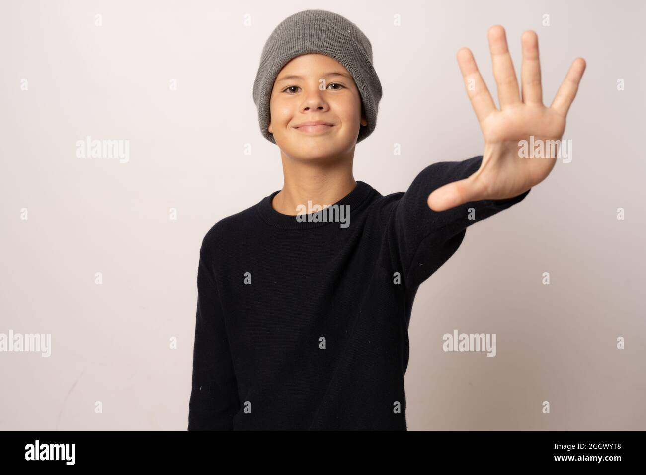 Portrait of a young boy smiling wearing a woolen hat on white background Stock Photo