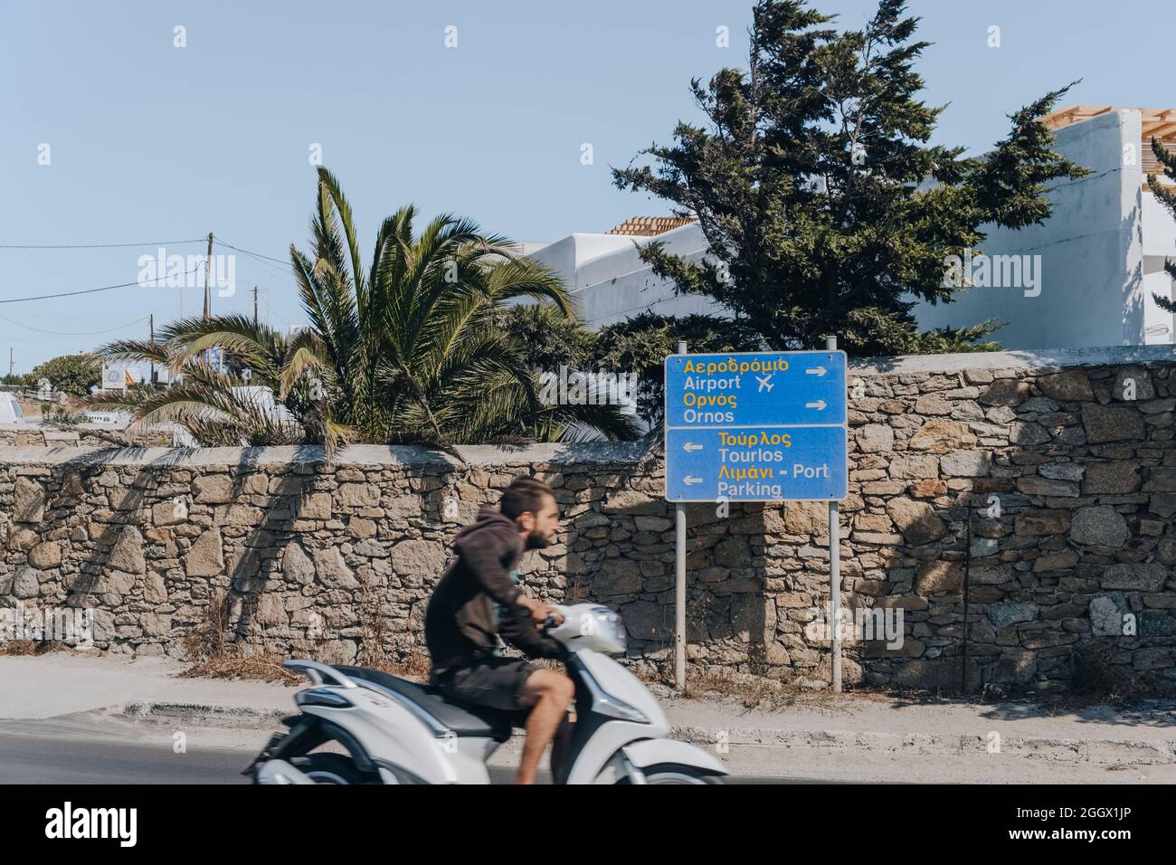 Mykonos, Greece - September 24, 2019: Bilingual directional sign to towns, port and airport on a road in Mykonos, a popular tourist destination in Gre Stock Photo
