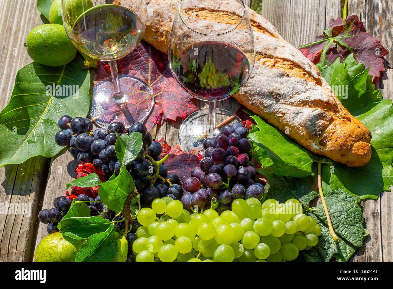 Symbolbild Weinlese: Reife Weintrauben mit Weingläsern dekoriert auf einem Holztisch Stock Photo