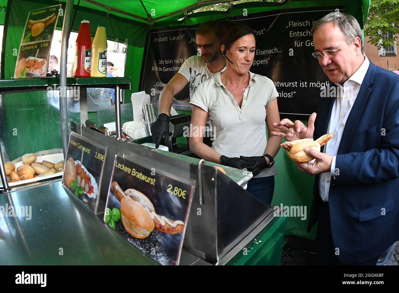 Eisenach, Germany. 03rd Sep, 2021. Armin Laschet (CDU), candidate for chancellor of the CDU/CSU and prime minister of North Rhine-Westphalia, is standing at a bratwurst stand on the sidelines of an election campaign event on the market square with a bratwurst in his hand, talking to saleswoman Yvonne Polivka about Thuringian bratwursts and her work. Credit: Swen Pförtner/dpa-Zentralbild/dpa/Alamy Live News Stock Photo