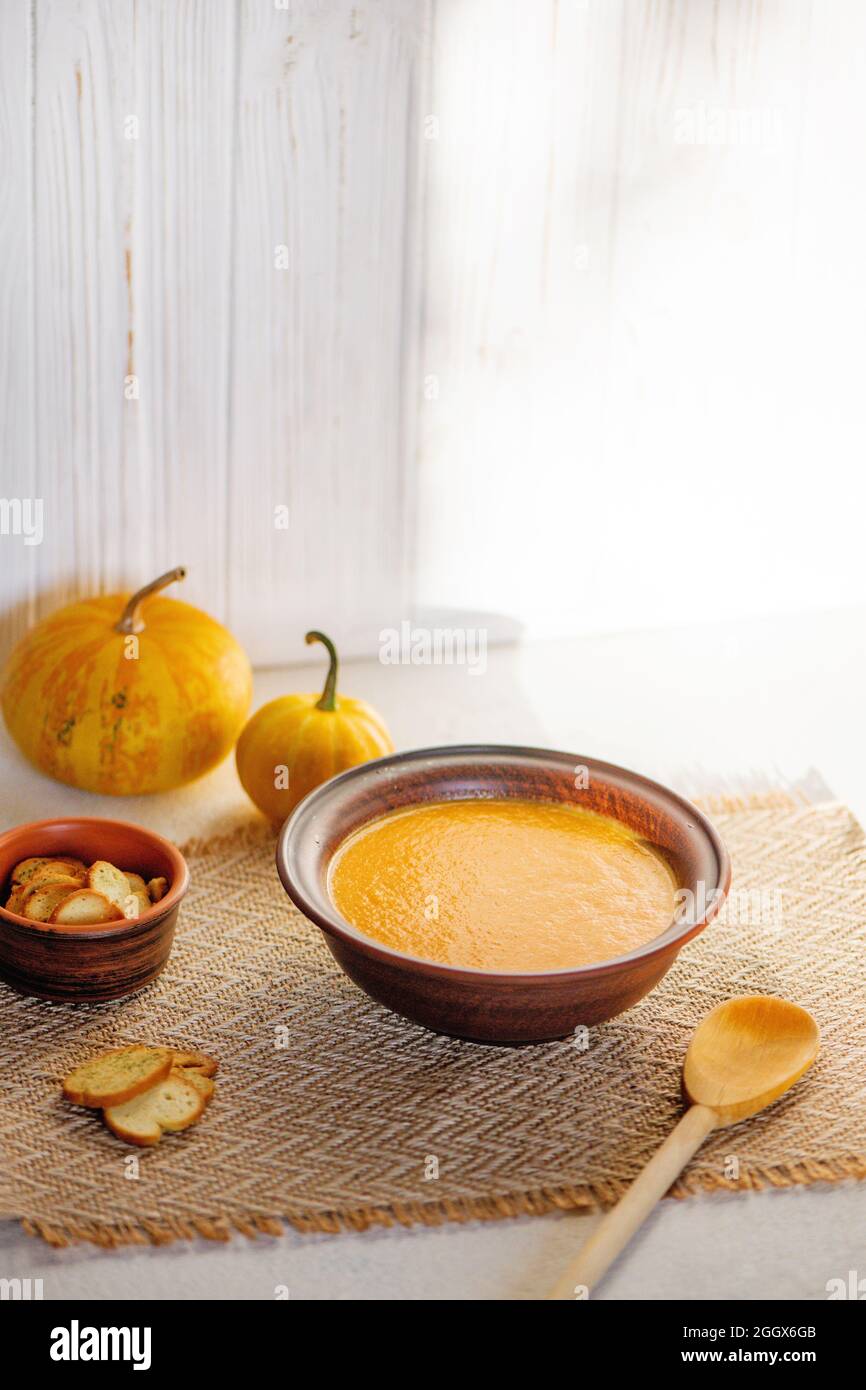Pumpkin soup in ceramic bowl on white wooden background. Stock Photo