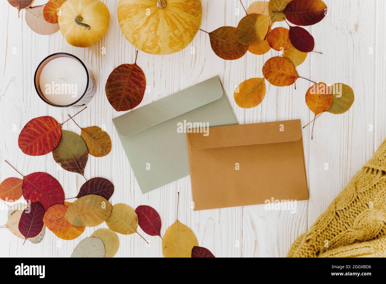 Flat lay composition with envelops, pumpkins, candle and autumn leaves on white background. Stock Photo