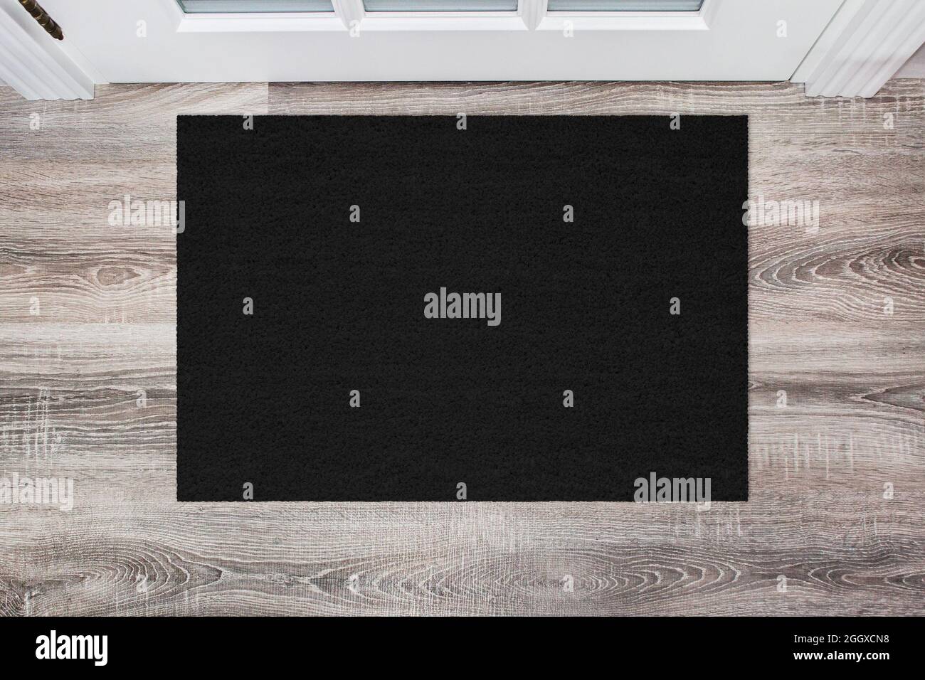Black Coir Doormat on wooden floor in front of the door. Product mockup Stock Photo
