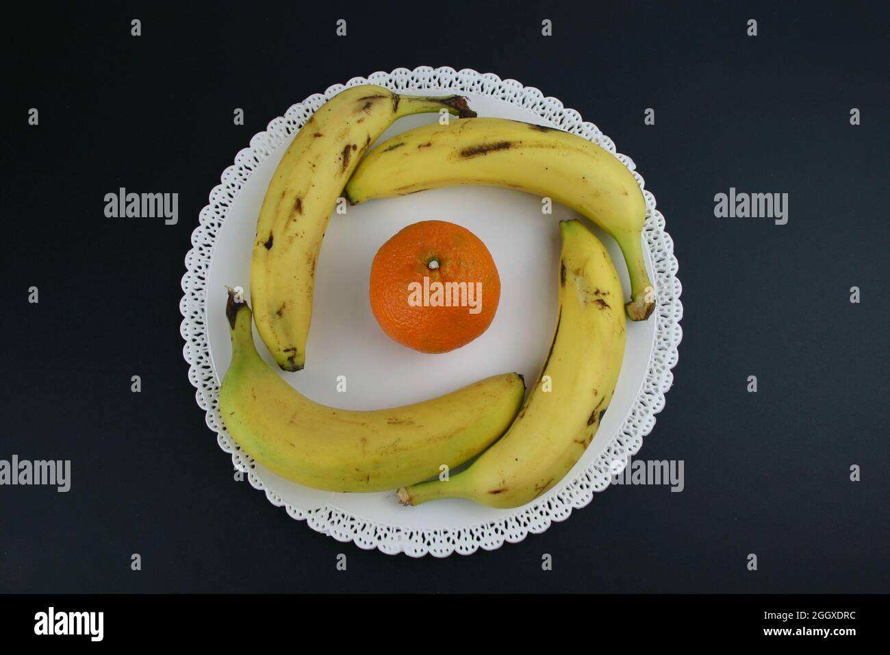 Essen Früchte 4  Bananen und 1 Orange auf einen weißen Teller Stock Photo