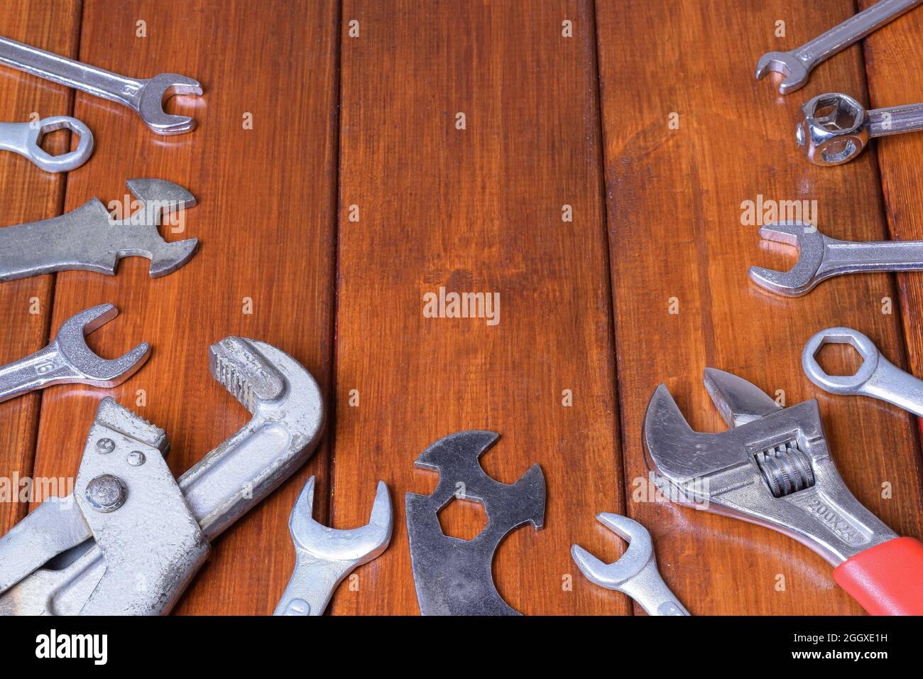 Different types of wrenches lie on a wooden background spread out below