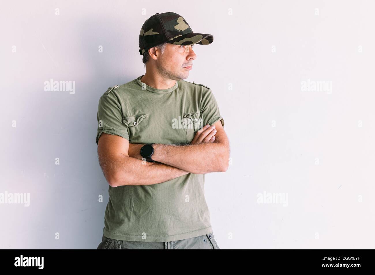 Military man with camouflage cap, arms crossed, on a white wall Stock ...