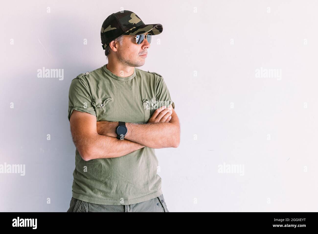 Military man with sunglasses and camouflage cap, arms crossed, on a ...