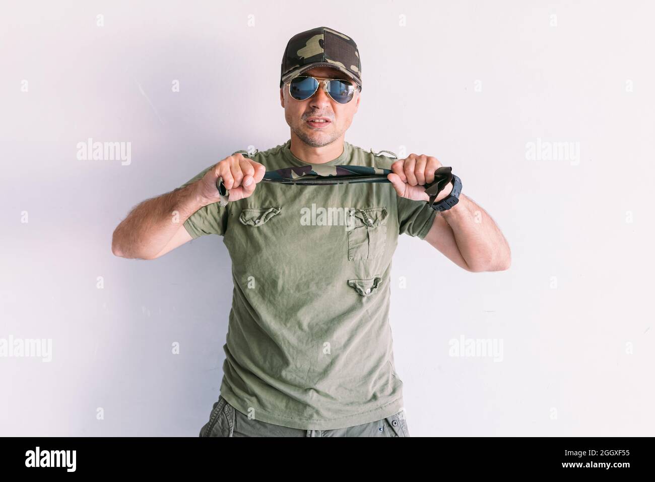 Military man with camouflage cap and sunglasses, clutching a camouflage ...