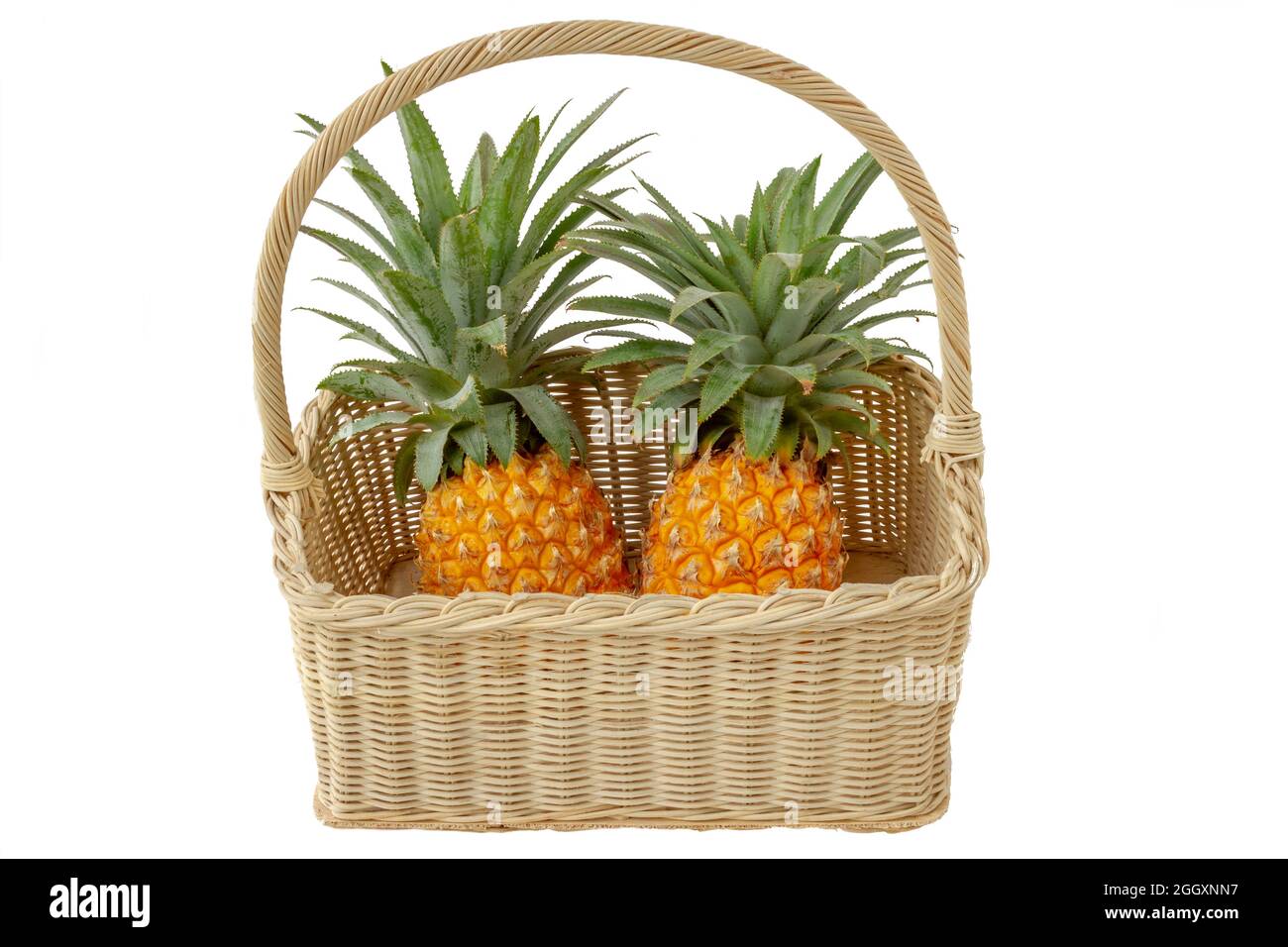 isolated fruit with a clipping path, two yellow-orange pineapples with a fruit basket Stock Photo
