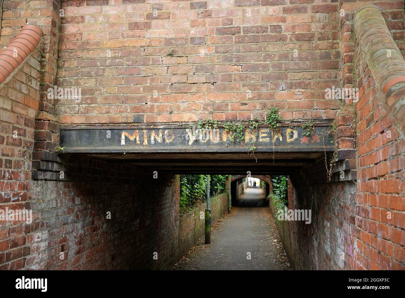 Mind Your head painted onto a low bridge over a footpath in Royal Leamington Spa in the West Midlands, UK. Stock Photo