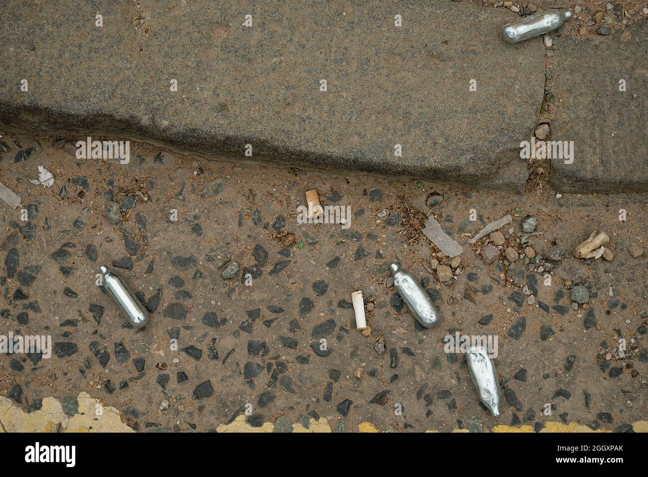 Nitrous Oxide gas canisters discarded on a street corner. Small silver