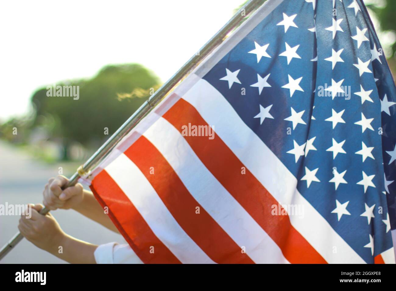 Person waving the American flag outside. Stock Photo