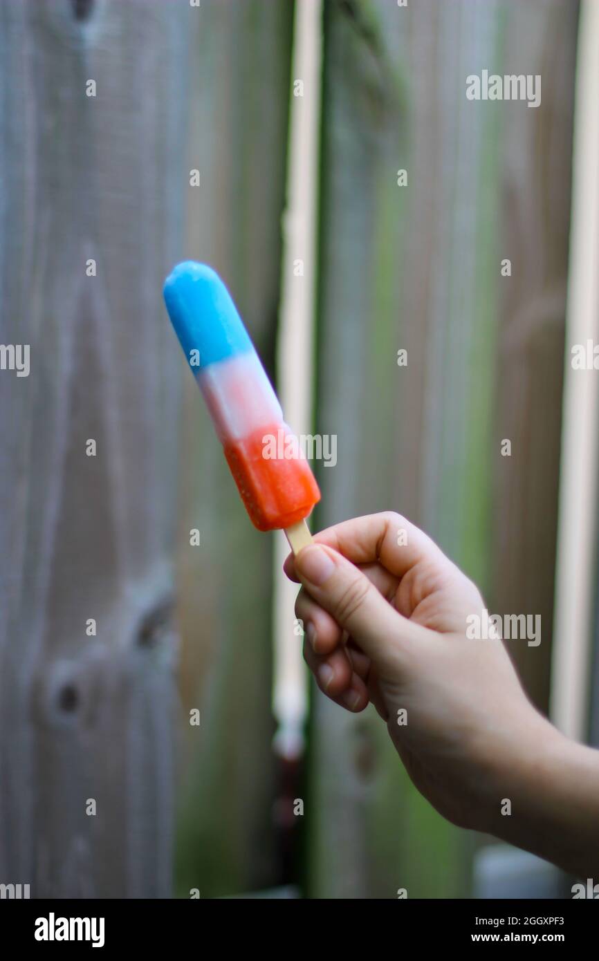 Person holding a Rocket popsicle, red white and blue frozen popsicle for the 4th of july. Stock Photo