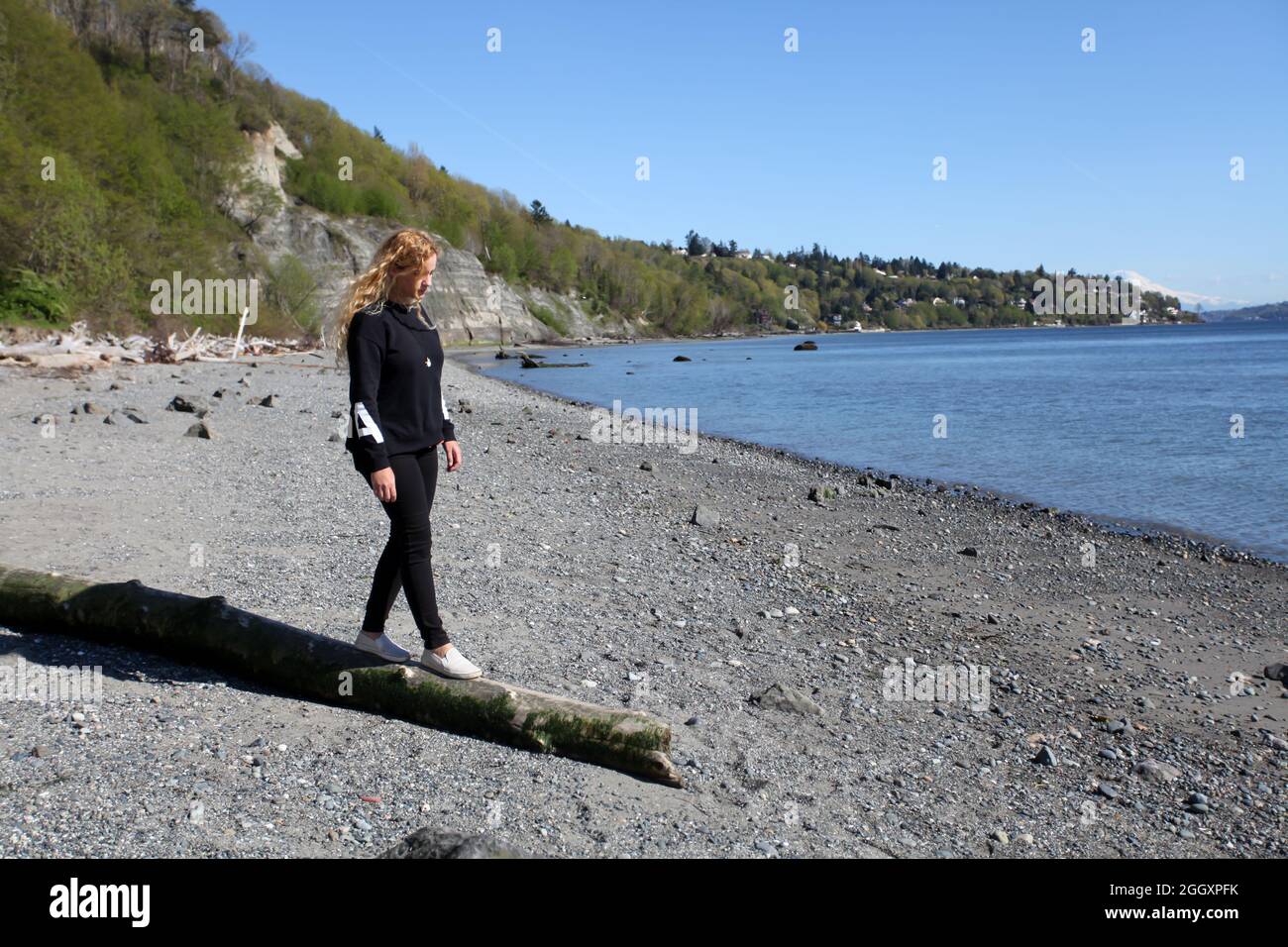 Woman walking on a log along the beach in Seattle, Washington. Stock Photo