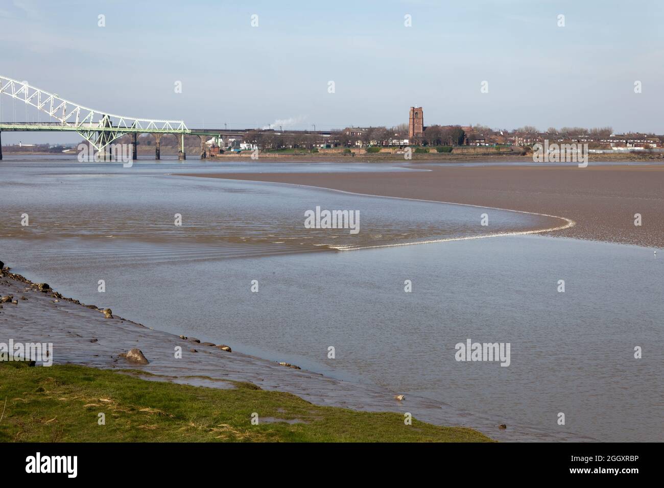 The Mersey Tidal Bore approaching Wigg Island Community Park in Runcorn with the Silver Jubilee Bridge in the background Stock Photo