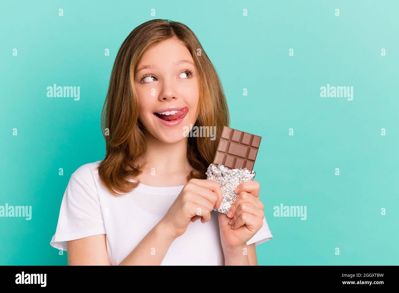 Photo portrait girl smiling happy eating chocolate plate licking lip looking copyspace isolated vivid teal color background Stock Photo