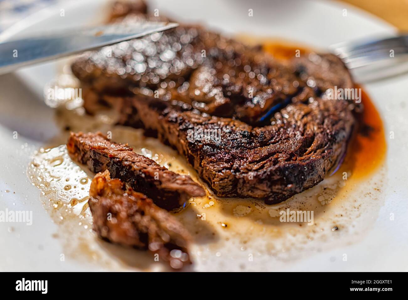 Closeup of knife slicing cutting cooked medium rare well done grilled grassfed ribeye rib eye
