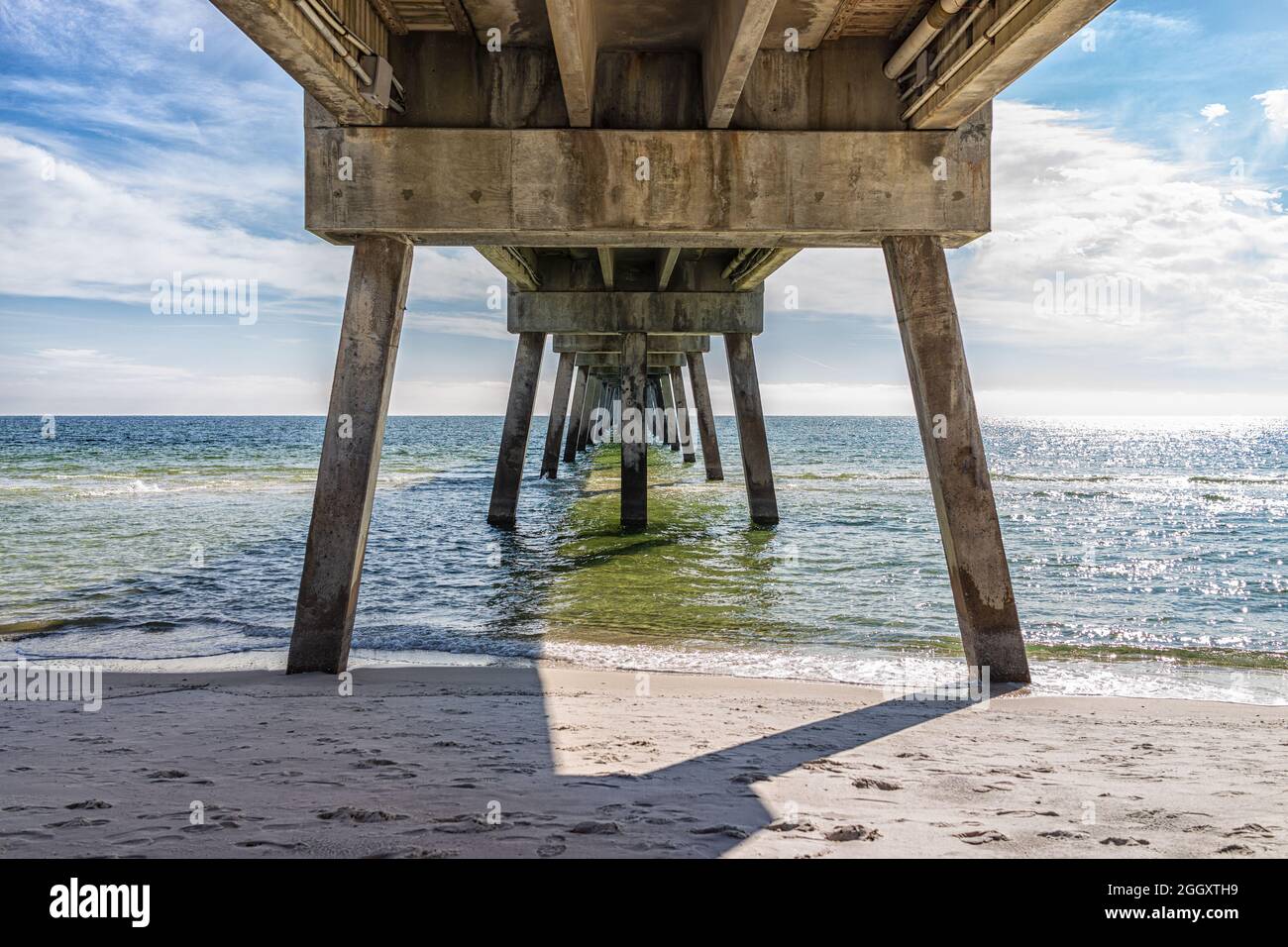 Under famous Okaloosa Island fishing pier in Fort Walton Beach, Florida winter season with pillars, green waves in Panhandle, Gulf of Mexico emerald c Stock Photo