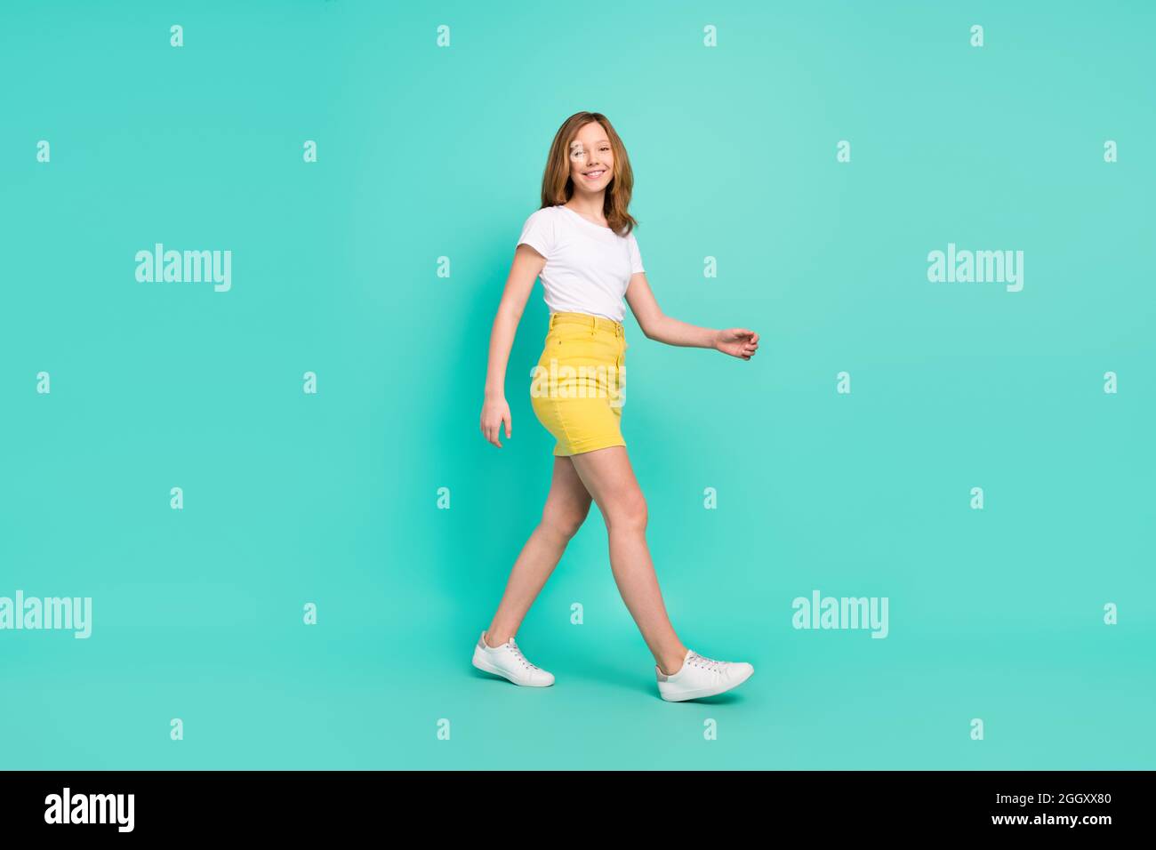 Full length body size photo smiling schoolgirl walking forward isolated vivid teal color background Stock Photo