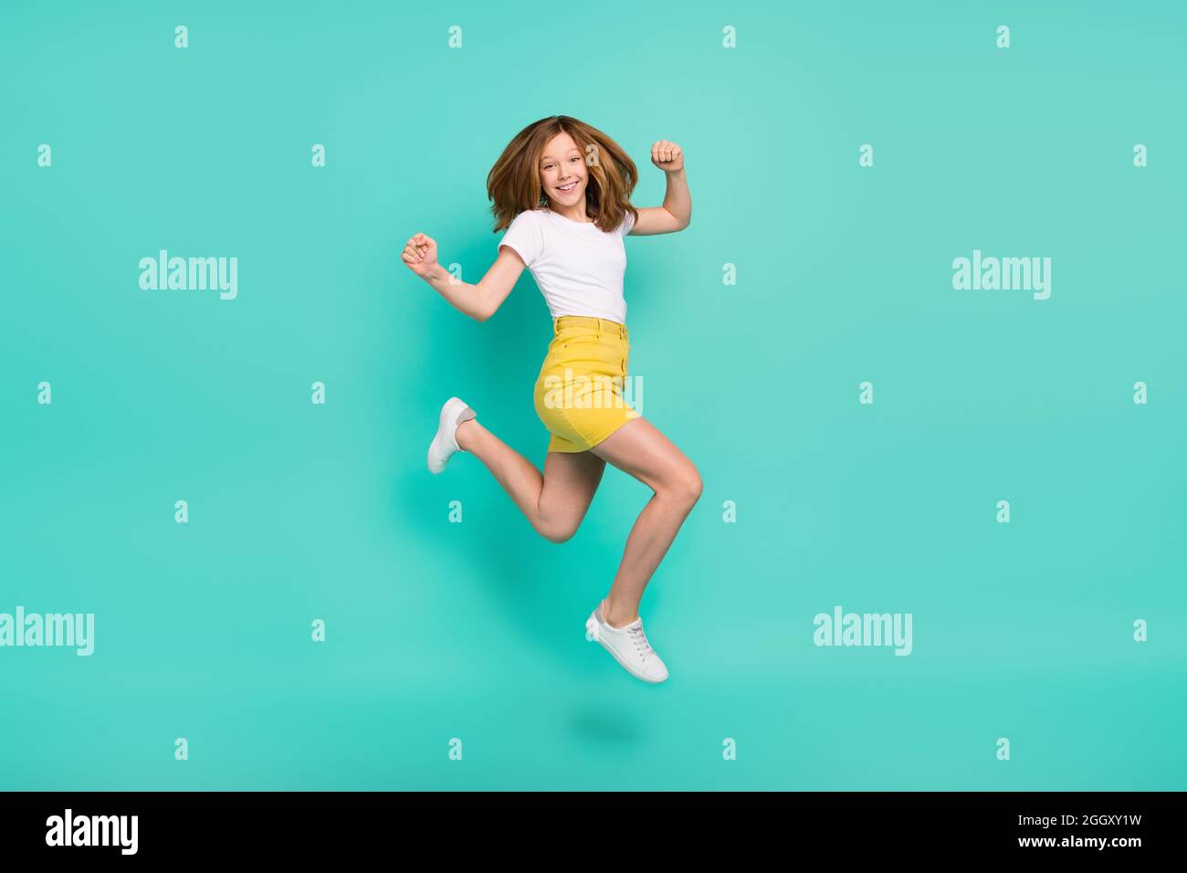Full length body size photo schoolgirl jumping up gesturing like winner isolated vivid teal color background Stock Photo