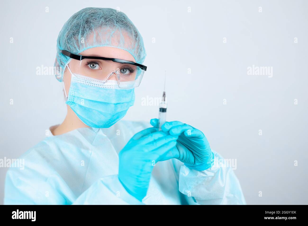 A nurse in a medical gown, mask and protective gloves with transparent ...