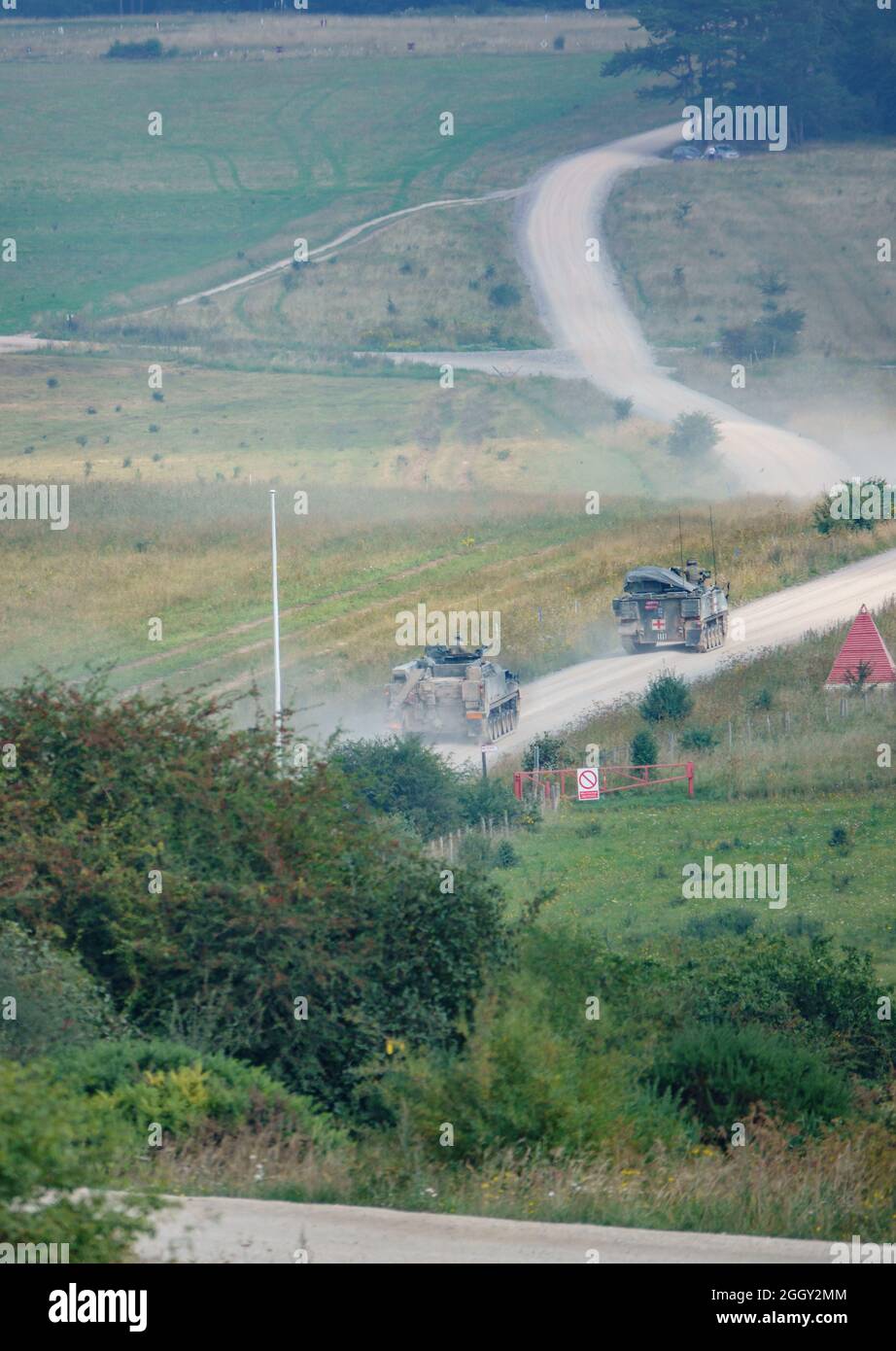 British army Warrior FV512 MRV and Bulldog FV432 ascend a dusty track on exercise, Wiltshire UK Stock Photo