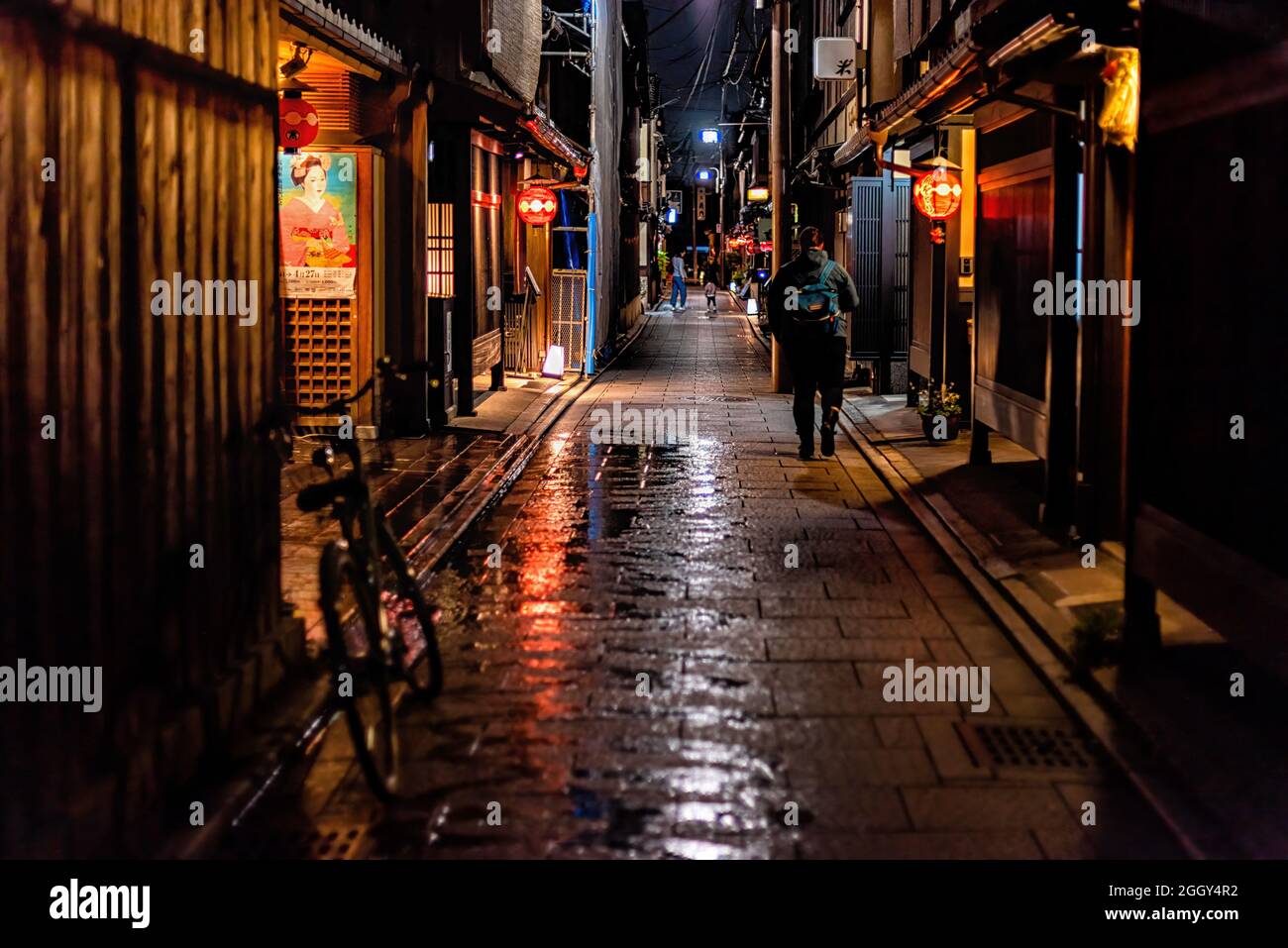 Kyoto, Japan - April 16, 2019: Gion district street alley at night road with reflection after rain and people walking as nightlife and geisha poster Stock Photo