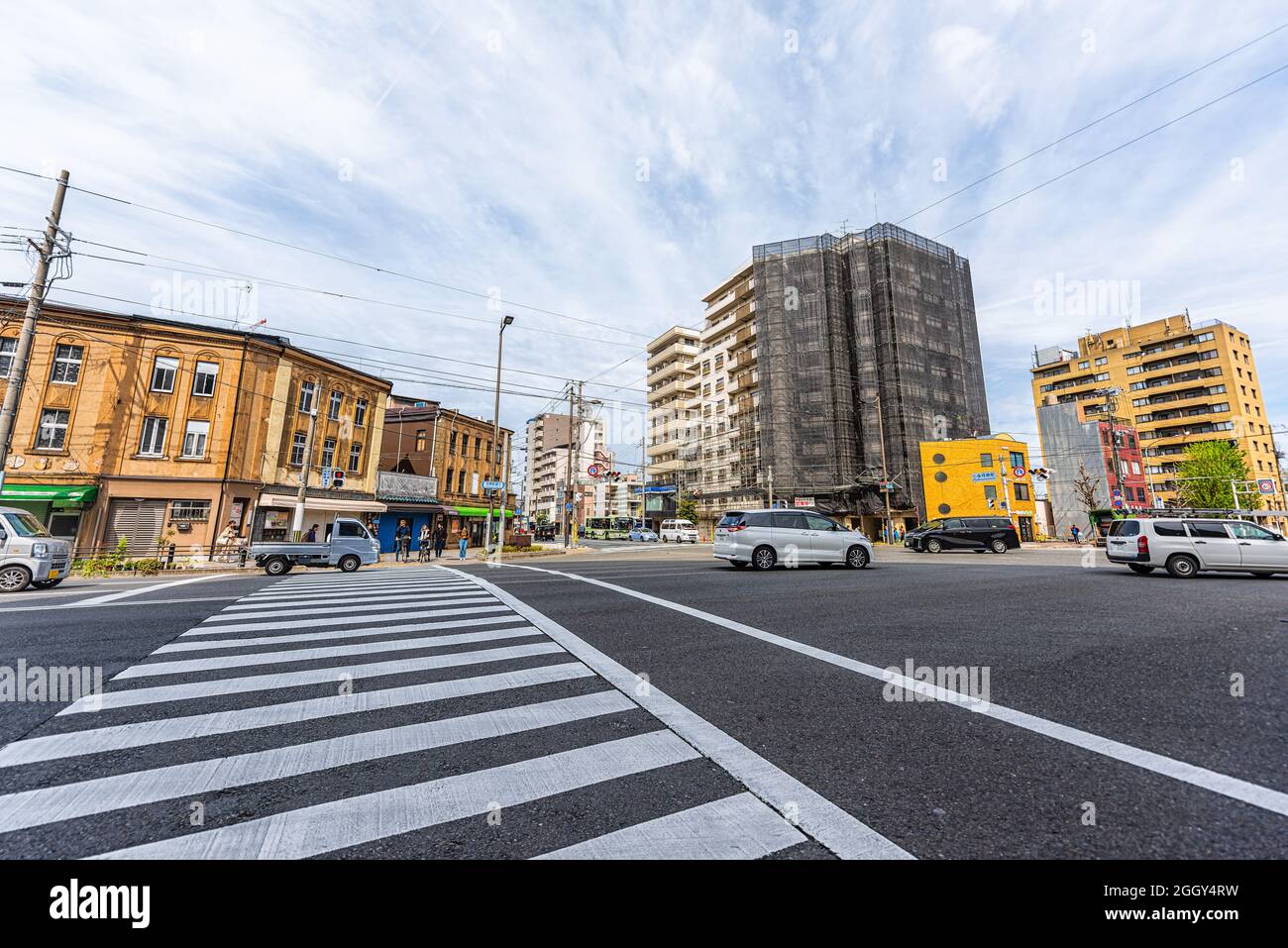 Kyoto, Japan - April 16, 2019: City street crossing crosswalk wide angle view during sunny day morning near train station with traffic Stock Photo