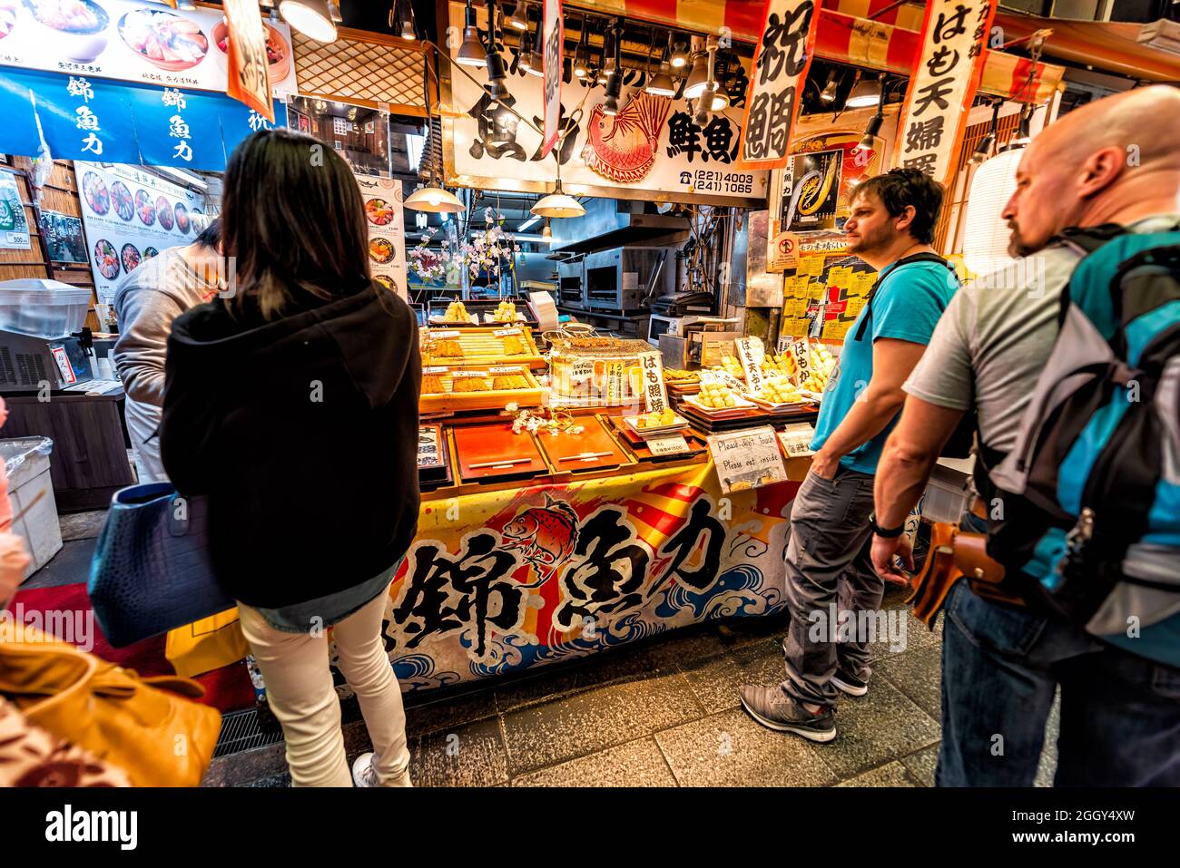 Kyoto, Japan - April 16, 2019: People shopping waiting in line queue at Nishiki market shops food vendor selling dango mochi food sweets Stock Photo