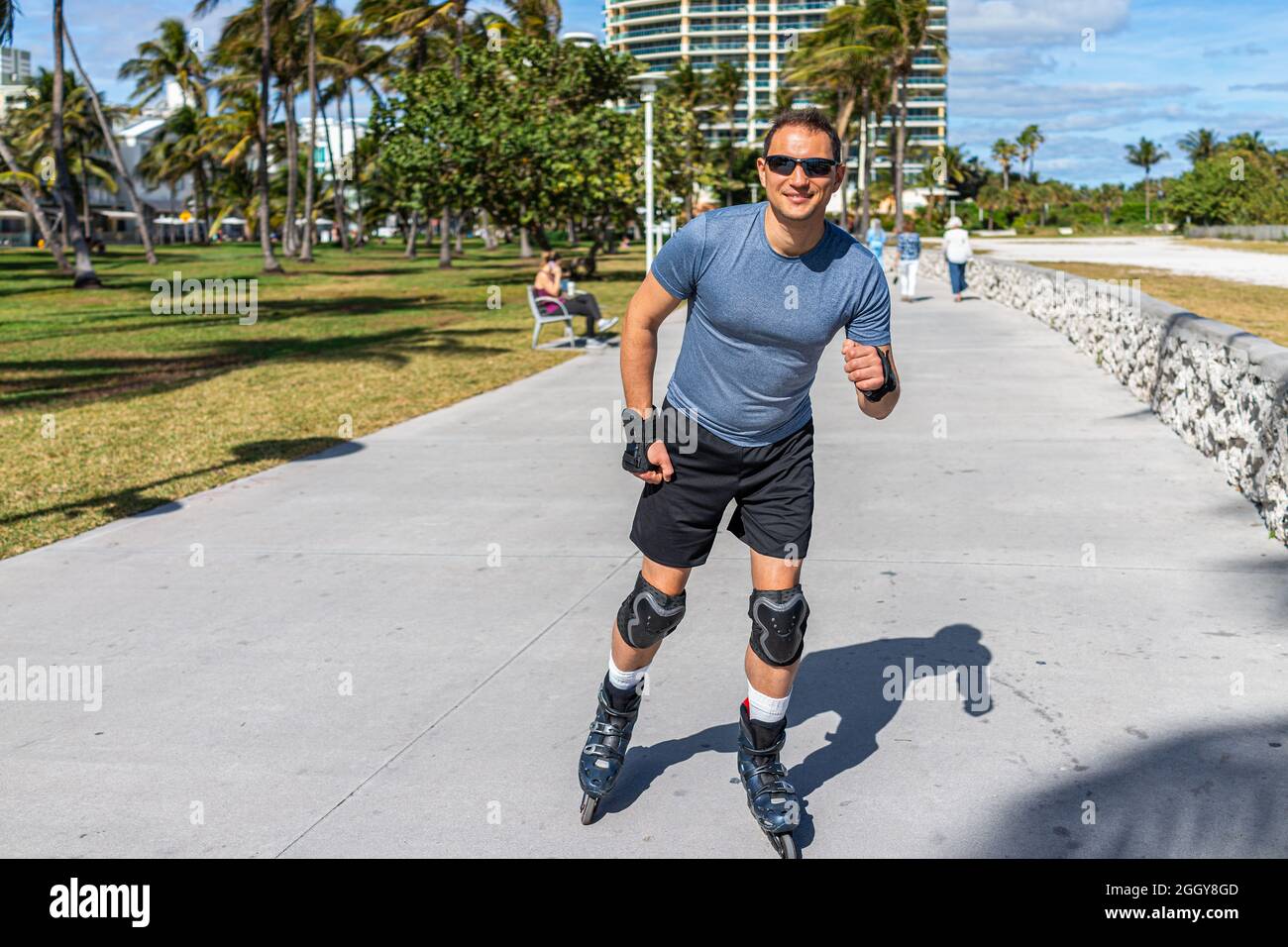 Young fit man roller skating on ocean walk boardwalk at Lummus public park by Ocean drive of South Beach, Florida with protective knee hand palm pads Stock Photo