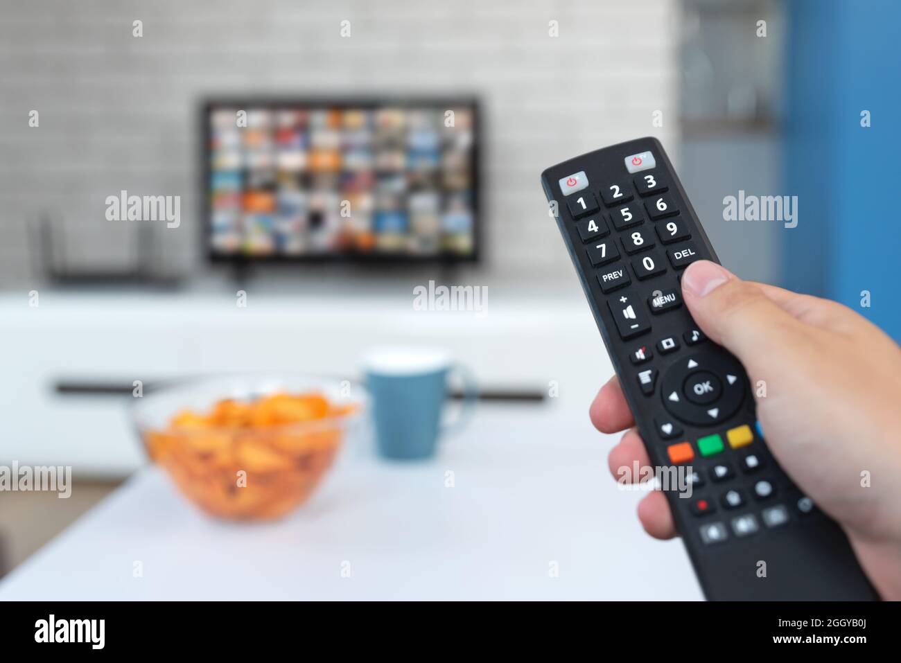 Man watching TV, remote control in hand. VOD service on TV Stock Photo