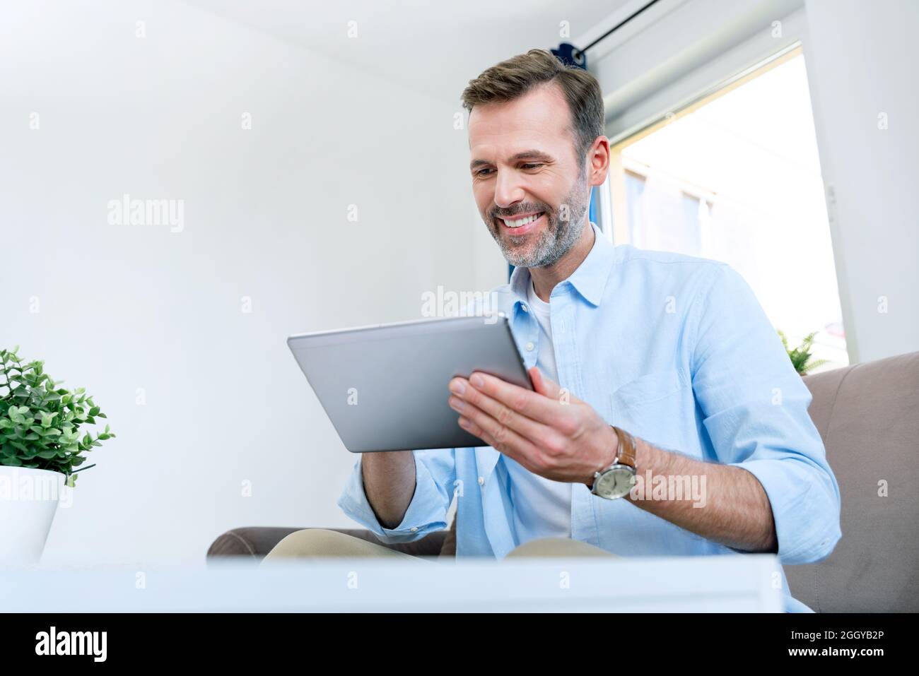 Handsome businessman working from home. Using app on tablet to telecommuting or sales reporting Stock Photo