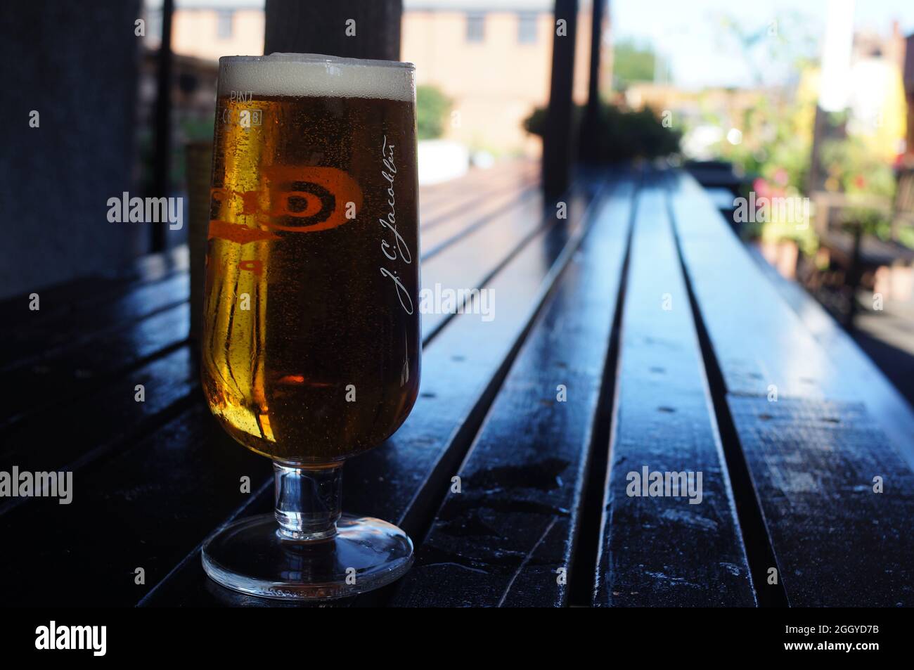 A pint of beer on a wooden tabletop with naturally lit, soft focused  background Stock Photo